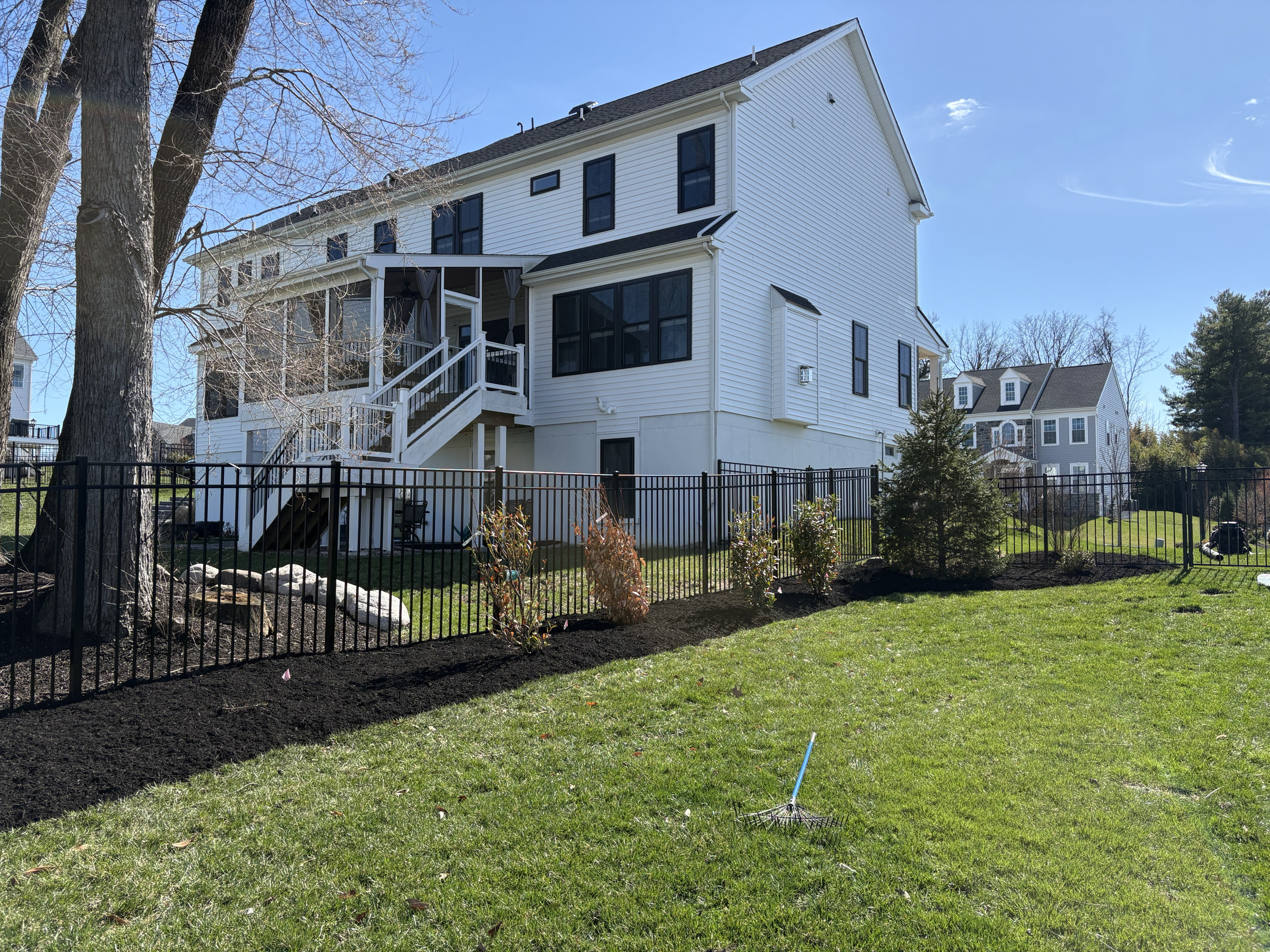 Fresh dark mulch beds with newly planted shrubs along a fence line in Glenside, PA